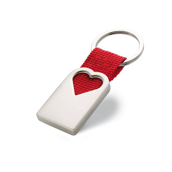 Key ring with logo BONHEUR Key ring with logo in metal, in mat pearl finish in hollow heart shape decoration. With polyester webbing holding the metal ring. Individual gift box. Available color: Red Dimensions: 5,5X2,5X0,6 CM Width: 2.5 cm Length: 5.5 cm Height: 0.6 cm Volume: 0.11 cdm3 Gross Weight: 0.036 kg Net Weight: 0.027 kg Depending on the surface we can use embroidery, engraving, 360° imprint or screen print.