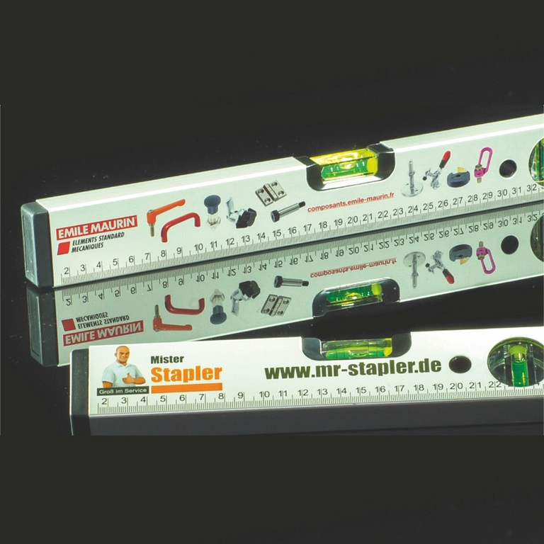 Level with logo Alu or Wood Spirit levels produced to meet professional demands. From a length of 30 cm they are fitted with a vertical and horizontal bubble. Each of these is contained in shatter-proof Plexiglass and is precisely adjusted. Due to a high measuring accuracy of 0.5 mm per metre= 0.0285 ° these spirit level are extremely suitable for all professional leveling work. Produced following quality features from 30 cm: 1.     Aluminum profile 1.7 mm thick and therefore very impact-resistant and rigid in windy conditions. 2.     cm scaling on the front for various measurements 3.     Horizontal bubble with double rings for exact readings from 2 % slope (floors in sanitary areas, patios, drainpipes etc.) 4.     Bubble with magnification effect provides 30 % optical enlargement for better readings. 5.     Fluorescent horizontal bubble illuminates in dusk and darkness. This makes reading in poor light significantly easier. 6.     Very high measurement accuracy of 0.0285 % in normal situation. 7.     30 years guaranty* on the bubbles with enclosures.     Magnus Business Gifts is your partner for merchandising, gadgets or unique business gifts since 1967. Certified with Ecovadis gold!